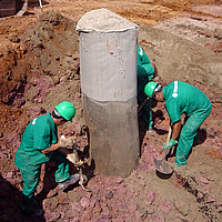 Workers shovel at a column encased and filled with Ringtrac®.