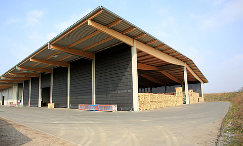 Large warehouse with open front and roof overhang. Long side is closed by six gray folding fronts