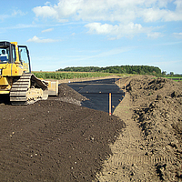 Bulldozer spreads soil over an already laid Basetrac Grid on the construction site