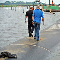 People walk over a completed dam