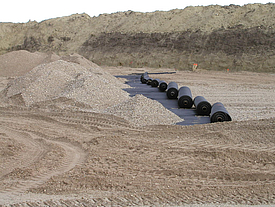 Gravel is tipped onto rolled-out Fortrac A geogrids made of high-strength aramid, ideal for soil reinforcement and sinkhole bridging